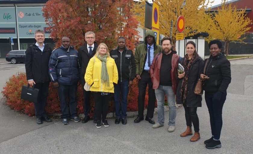 Masakas besöker Kalix, pelarrönnen i bakgrunden är också Kalix kommuns globträd. Från vänster: Björn Emmoth, Achilles Mawanda, Tommy Nilsson, Malin Huuva, Francis Kimuli, Juuko Winyi, Per Eriksson, Sara Cave, Juliet N Mayanja. Foto: Kalix kommun.