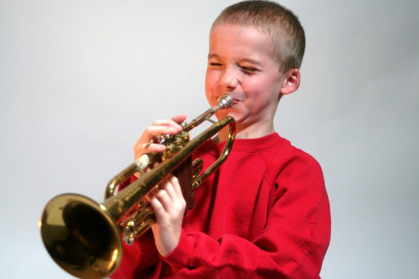 Pojke spelar brassinstrumentet trumpet.