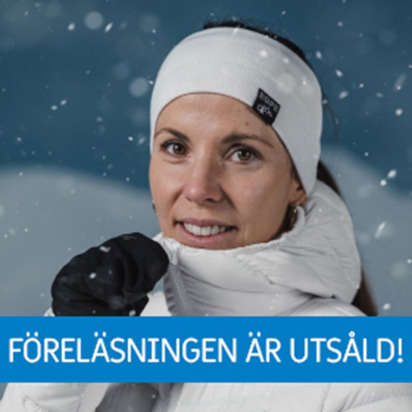 Porträttbild på Charlotte Kalla, iklädd en vit vinterjacka och ett vitt pannband i ett snöigt landskap. 